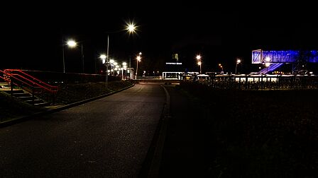 Station Barneveld Noord in de nacht. Er zijn meerdere lantaarnpalen bij de perrons. De fietsenstallingen en de traverse zijn fel verlicht. Er is geen treinverkeer meer