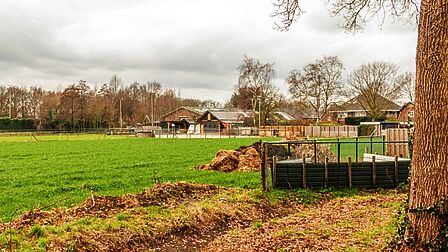 Paardenbak in een open gebied, naast een weiland, zichtbaar vanaf de weg. Als de paardenbak wordt verlicht, is het licht van veraf te zien