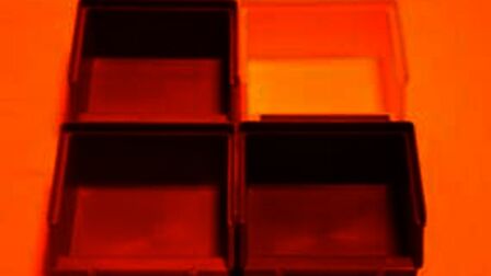 Bakjes van verschillende kleuren die verlicht worden met oranje licht, alles lijkt rood/oranje