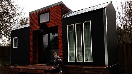 Een klein huisje met peuter die op een trappetje klimt